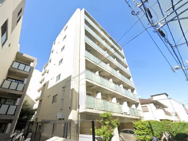 モダンな外観を持つマンション、バルコニー付きで周囲に建物が立ち並ぶ住宅街の風景