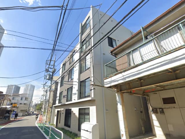 - 都市の高層ビルが背景に見える、モダンなデザインのアパート外観と街の風景、高圧線が横切る青空の下での景色