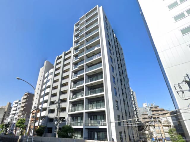 - 青空の下にそびえるモダンな高層マンション、バルコニーと大きな窓が特徴的な外観