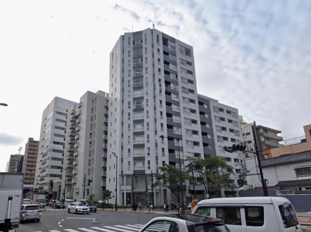 - 現代的なデザインの高層マンション、白と黒の外観、周囲に並ぶ他の建物と交通の様子を捉えた街の風景