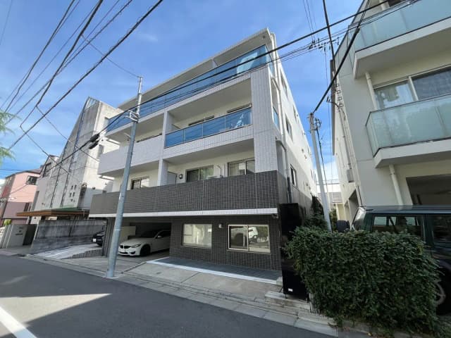 - モダンな外観のマンション、シンプルなデザインと大きなバルコニー、駐車スペースがある道路沿いの風景