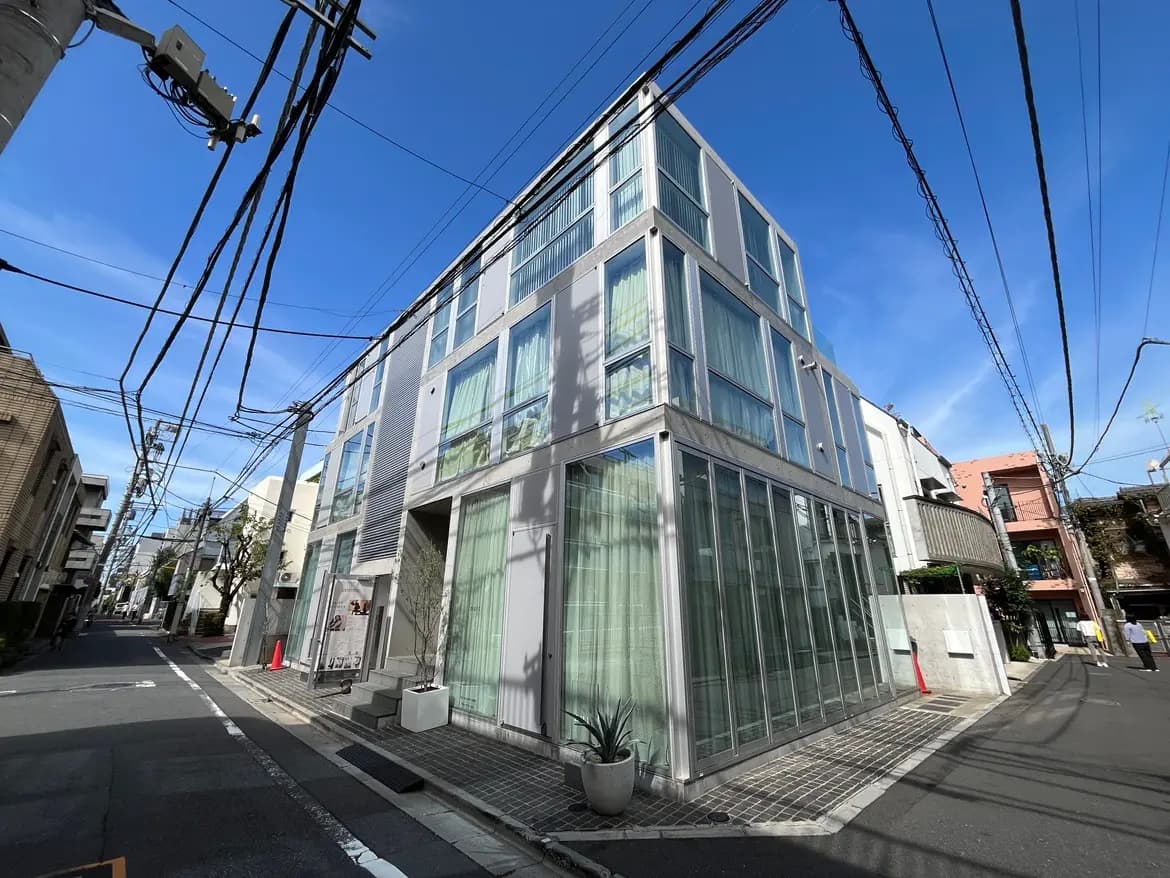 モダンな外観の建物、ガラス張りのファサードと青空、都市の路地に立つデザイン性の高い建物