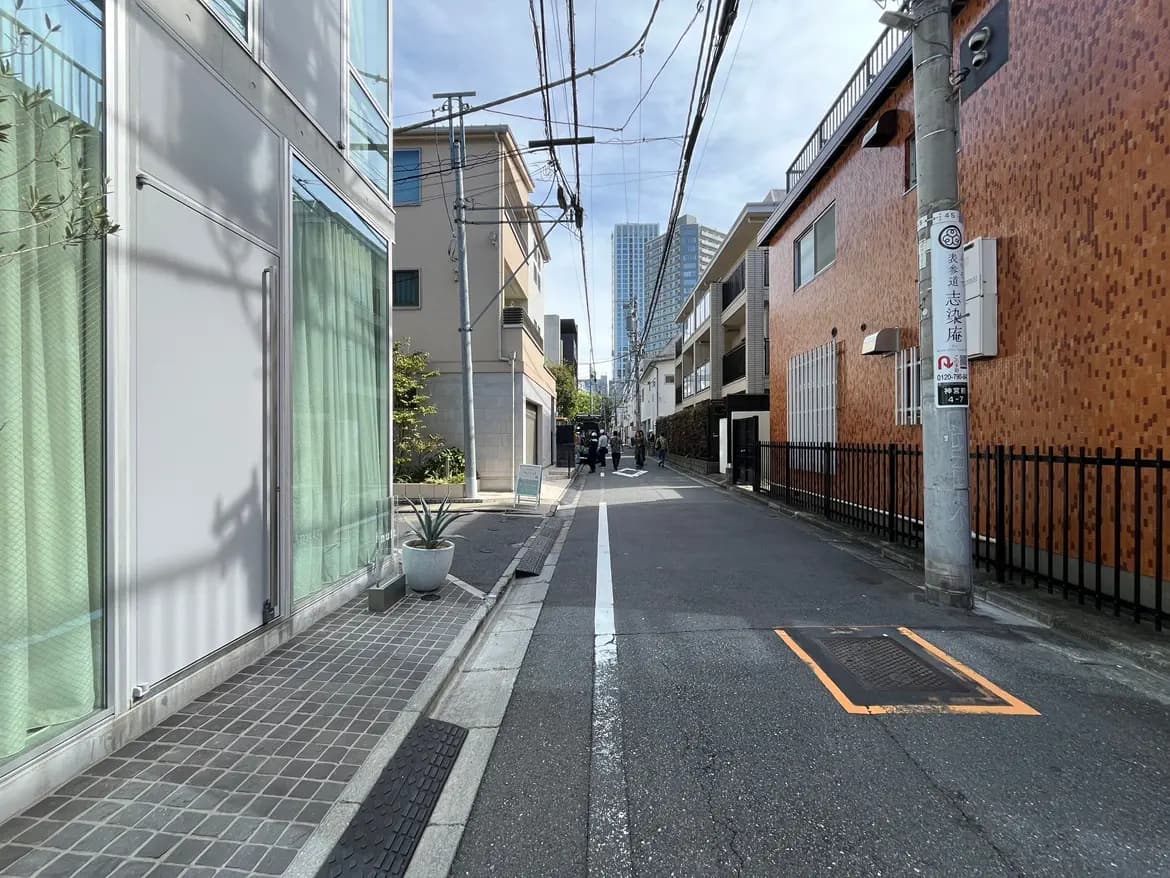 - 近代的な建物が立ち並ぶ都市の道、透明なガラスのファサードと温かみのある木材の外壁、路側に緑がある景観