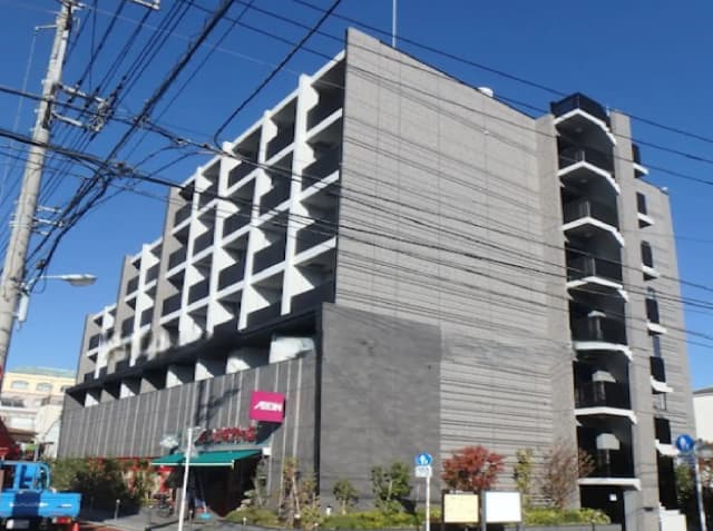 - 近代的なデザインの6階建てビル、外壁はグレーのタイル張りで、窓が印象的なファサード、照明と電線が交錯する都市の風景