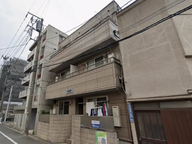 - 街中のアパートメントビル、ベランダには洗濯物が干され、周囲に電柱や電線が見える景観