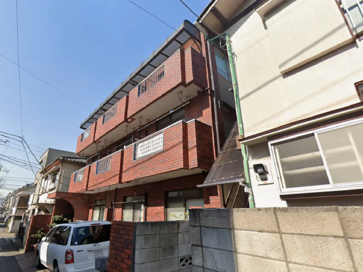 - 赤レンガの外壁を持つ3階建ての住宅、公道に面したバルコニーと駐車スペースのある建物の外観