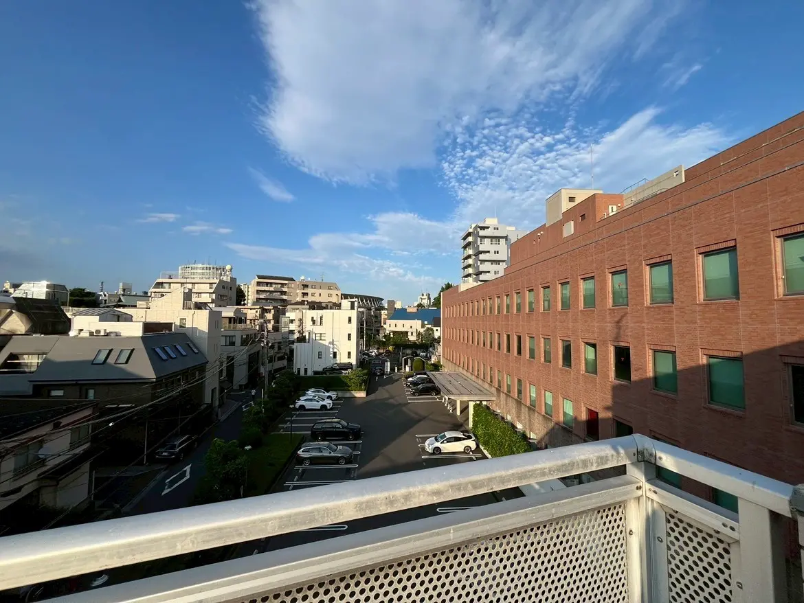 - 都市の風景、青空の下に広がる住宅と商業ビル、バルコニーから見た中庭と駐車場の眺め