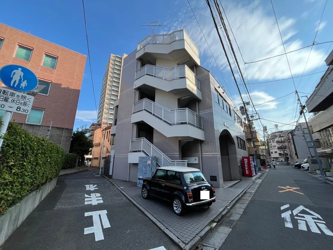 - 地元の住宅街にある外観のデザインが特徴的なビル、周囲には電柱と青空が広がる風景