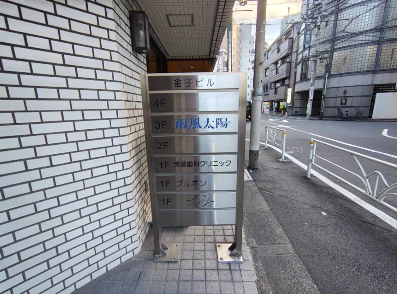 - 金子ビルのフロア案内看板、3階には「風太陽」、1階には「斉藤歯科クリニック」などの店舗名が表示されたスタイリッシュなサイン
