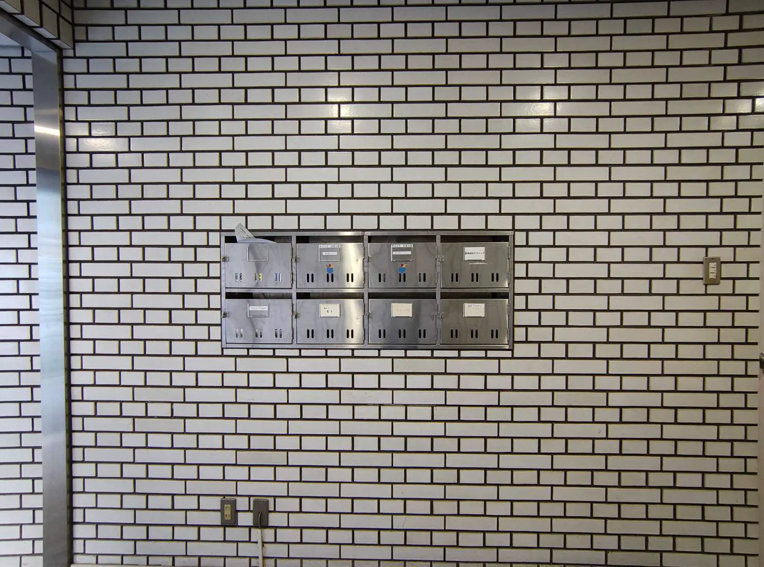 - 白いタイルの壁に埋め込まれた郵便ボックス、シンプルでモダンなデザインのインテリア