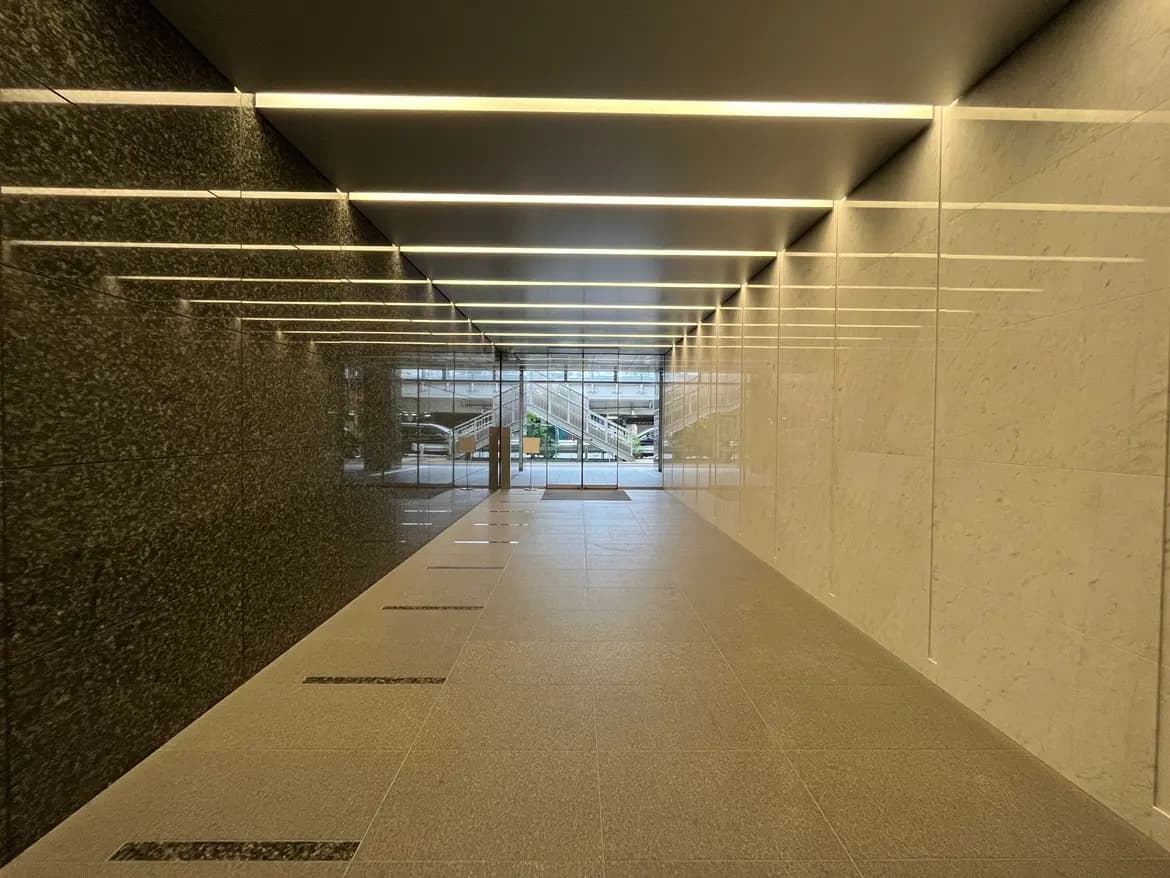 - モダンなデザインのロビー、滑らかな石壁と照明が整然と配置されたエントランス通路の風景