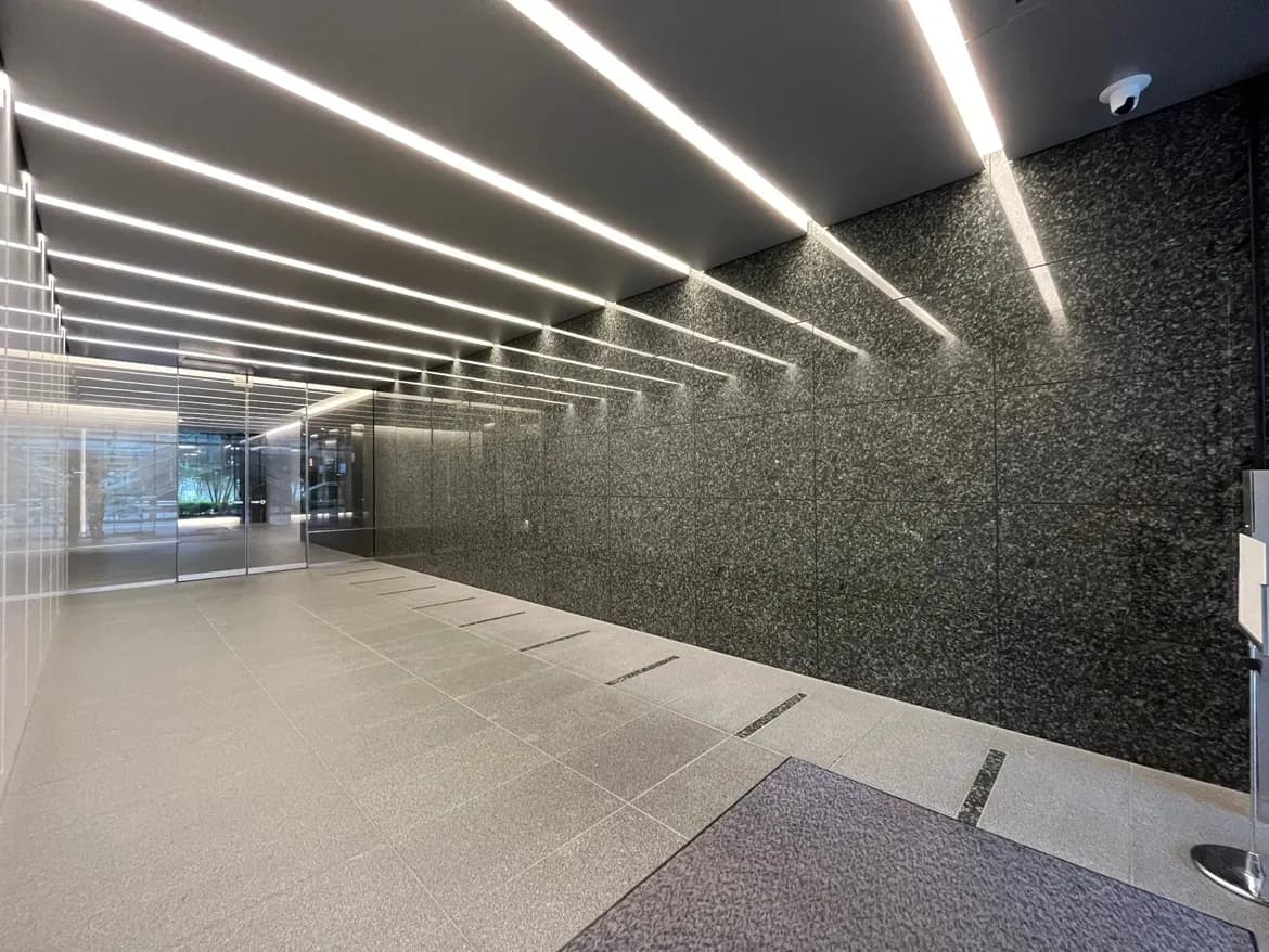 - 現代的なエントランスホール、黒い石材の壁と明るい間接照明が施されたシンプルなデザインの空間