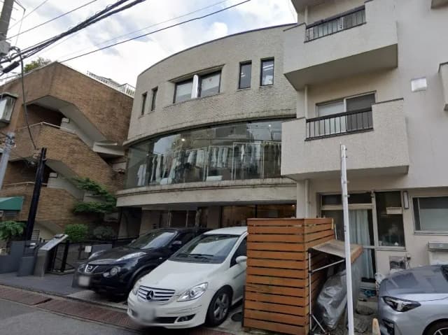 - 近代的なデザインの建物と駐車場、前面にガラスカーテンウォール、周囲に緑があるシーン