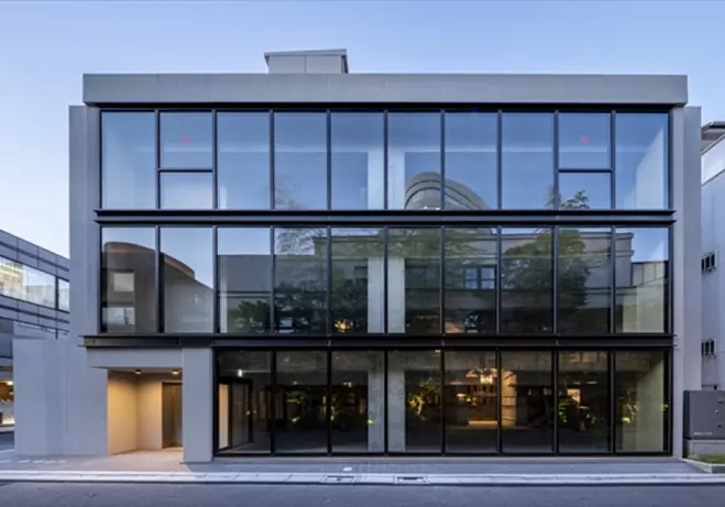 - モダンな外観の建物、ガラス張りのファサードとシンプルなデザイン、周囲の都市環境と調和した構造