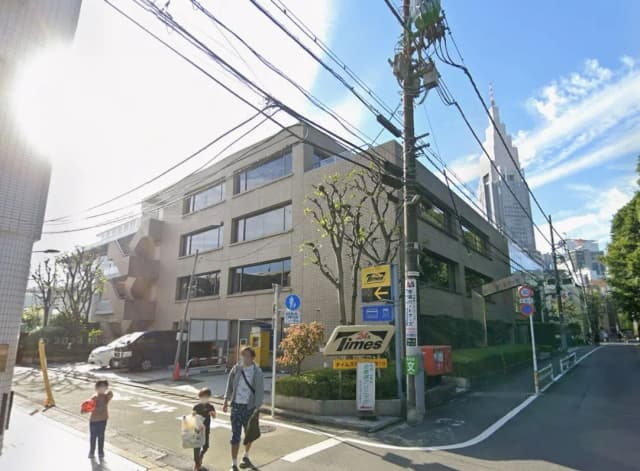 - 都市の風景の中にある現代的なビル、街路樹や電柱が立ち並ぶ交差点、晴れた青空が広がる環境