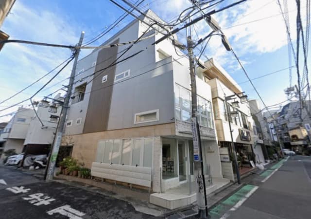 - 近代的なデザインの建物、窓が多く明るい外観、街中の風景と電線が交錯する通りの様子
