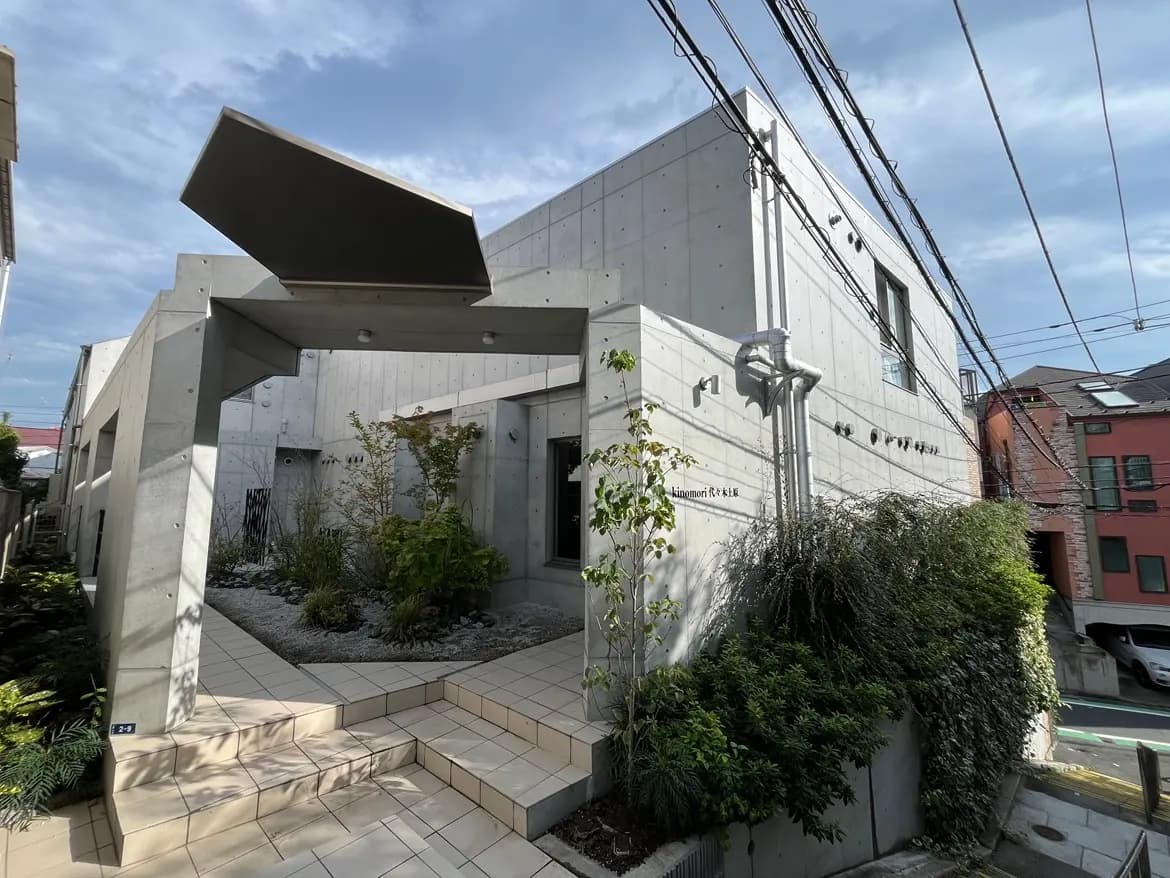 - コンクリート打ちっぱなしの外壁を持つ現代的な住宅、緑豊かな庭と整然としたアプローチが特徴的な外観