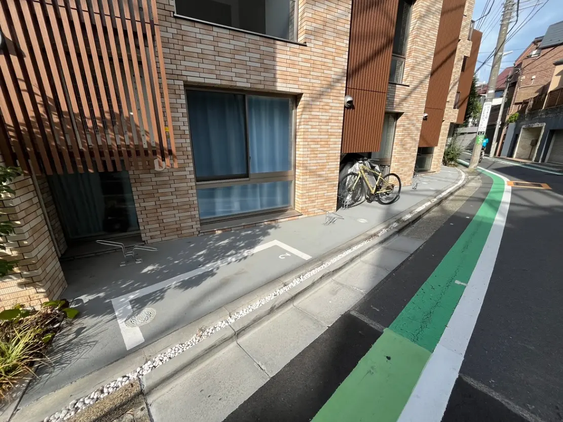 - モダンなレンガ造りの建物の外観、サイクリング用の自転車と整備された歩道、周囲の緑が感じられる街中の景観