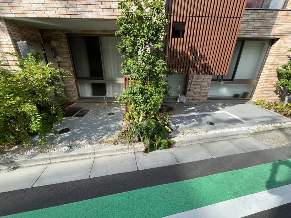 - 自然豊かな環境に囲まれたモダンな住宅のエントランス、緑の植栽と整備された駐車スペースが印象的な外観