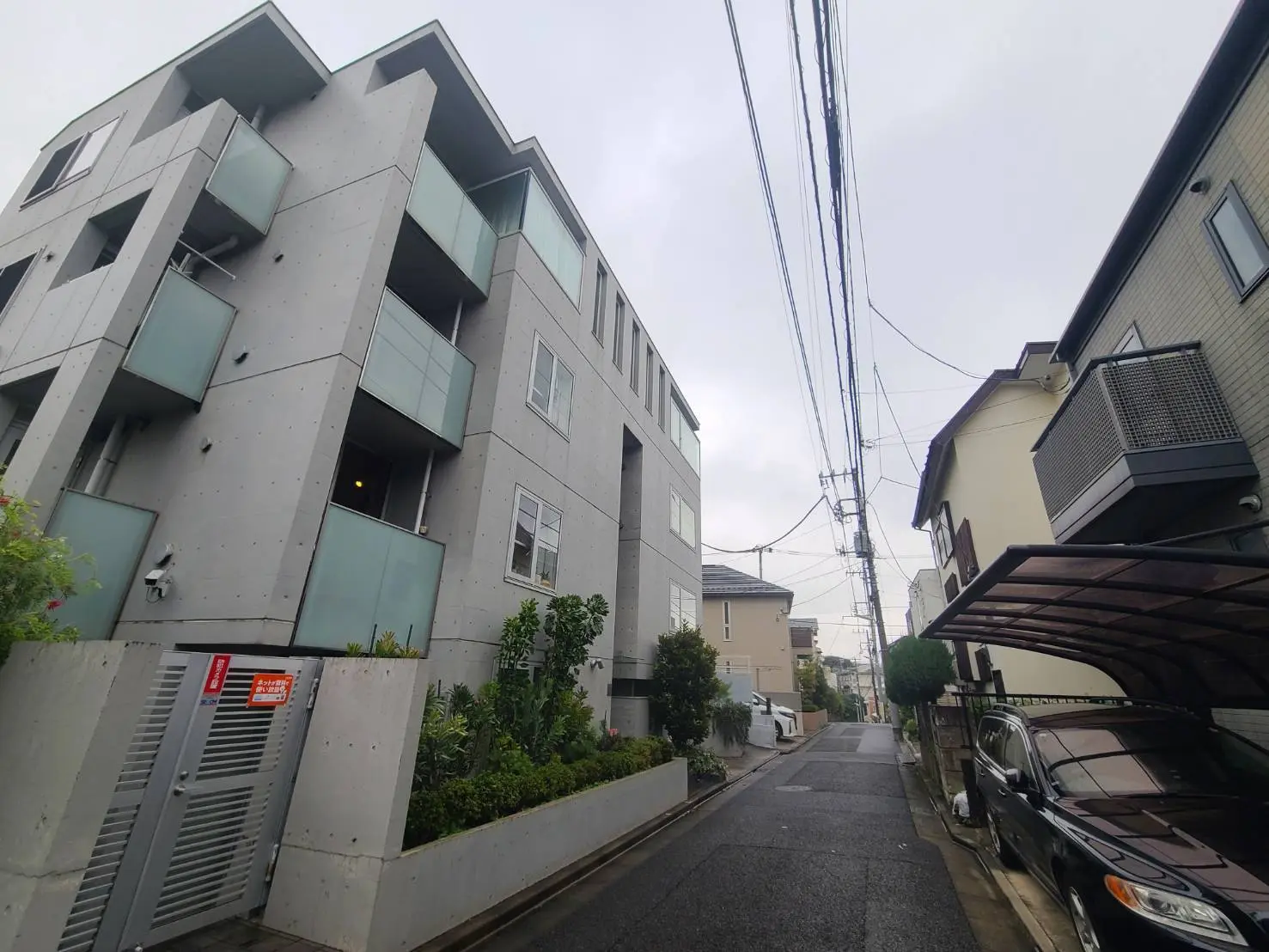 - 現代的なコンクリート建築のアパート、バルコニーと緑豊かな植栽がある通りの風景