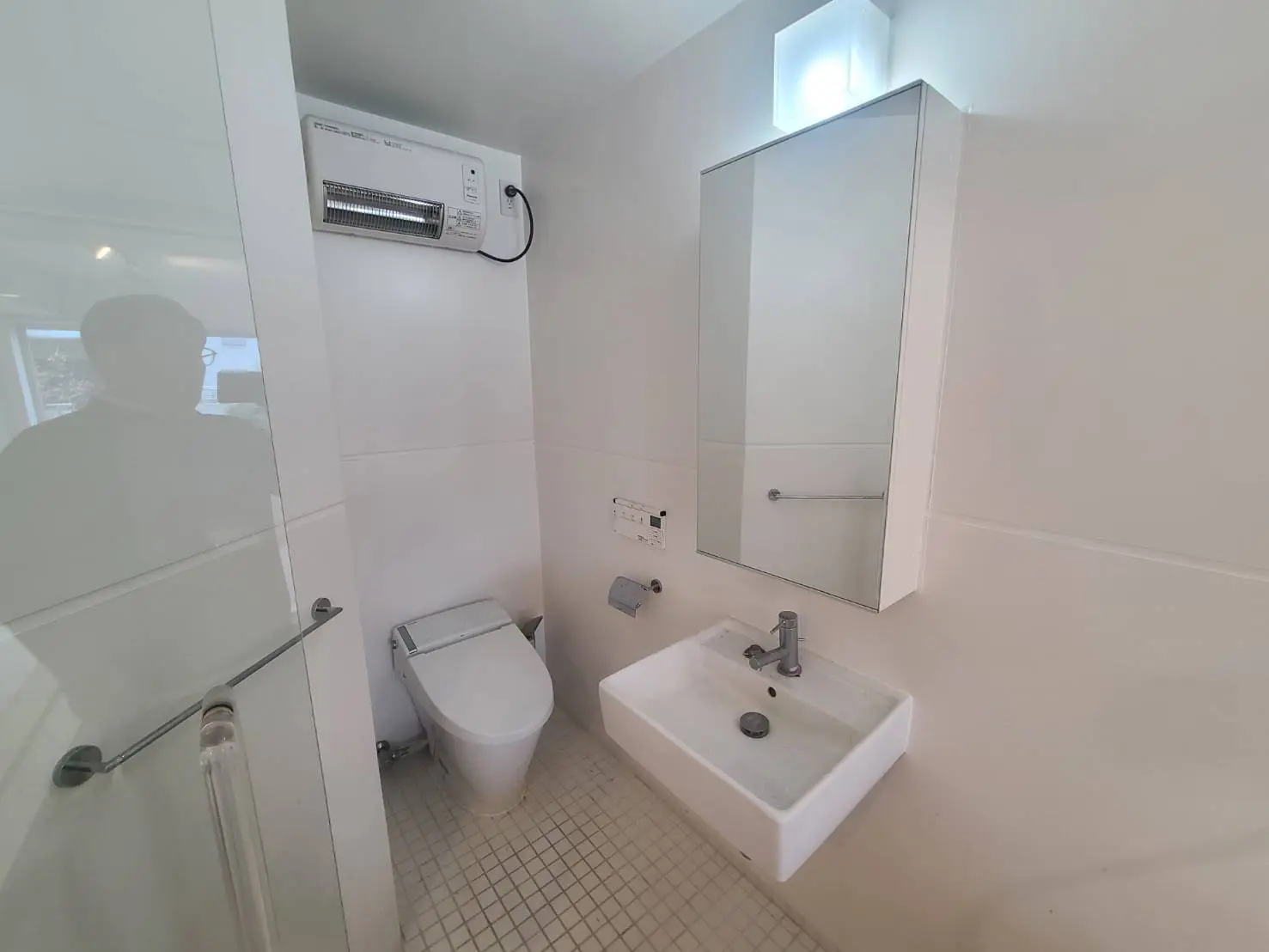 - モダンなデザインのバスルーム、白を基調とした内装、洗面台とトイレが配置された明るい空間