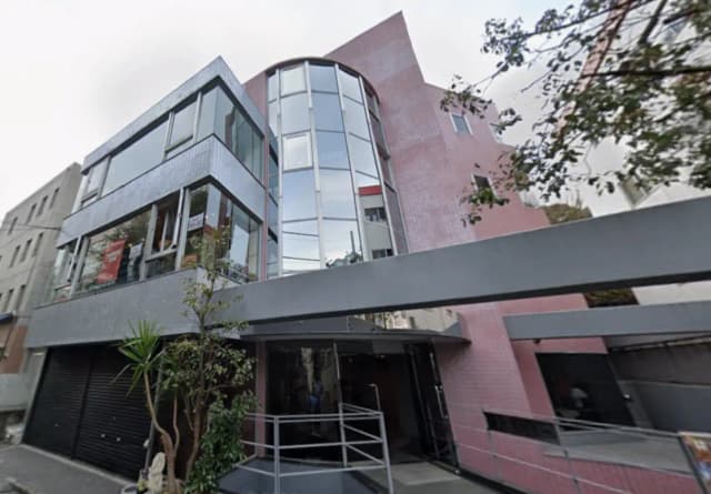 - 近代的な外観のビル、ガラス窓と赤いタイルの壁、緑の植物が施されたエントランスの景観