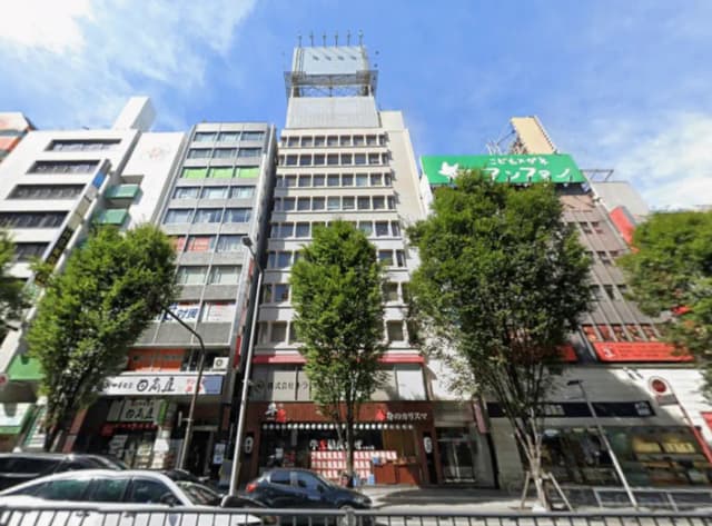 - 都市のビル群、緑の街路樹があり、様々な商業店舗が並ぶ賑やかな通りの風景