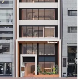 - 近代的な外観のオフィスビル、ガラス窓と木材のアクセントが施されたエントランス、都市の中心に位置する建物