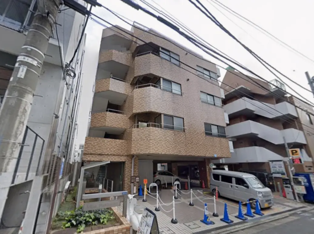 - 煉瓦調の外観を持つ現代的なマンション、エントランスと駐車場が整備されている商業エリアの風景