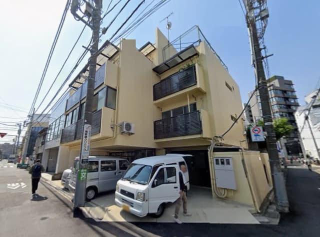 - 近代的なデザインの三階建て住宅、バルコニーと大きな窓が特徴、周囲に電柱と車がある通りの風景