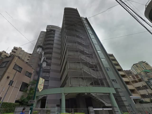 高層ビルの外観、現代的なデザインのファサードと階段、周囲の建物が写った都市の風景