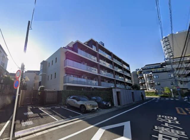 - モダンな外観のマンション、広々としたバルコニー、駐車場と周囲の住宅街が映る街の風景