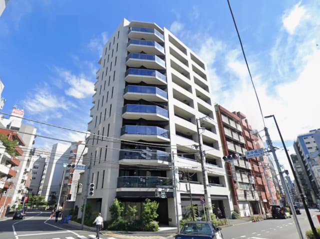 - モダンなデザインのマンション外観、バルコニーが特徴的で周囲には他の建物や交通信号が見える街の風景