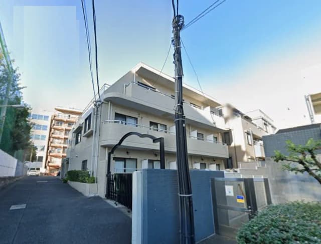 - 都心に位置するモダンなアパートメントの外観、周囲に他の建物があり、線路に沿った環境が特徴的な風景