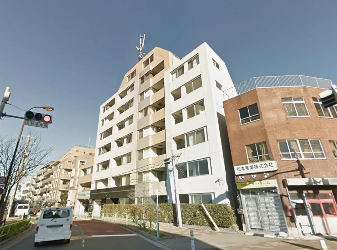 - 近代的な住宅ビルの外観、隣には商業施設があり交通信号と人行き道がある街の風景