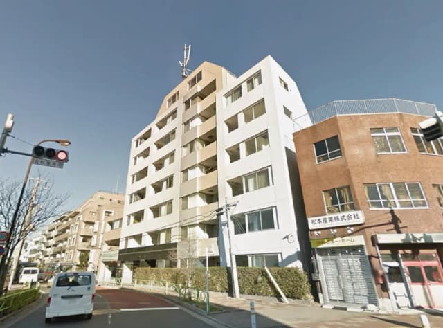 - 近代的な住宅ビルの外観、隣には商業施設があり交通信号と人行き道がある街の風景