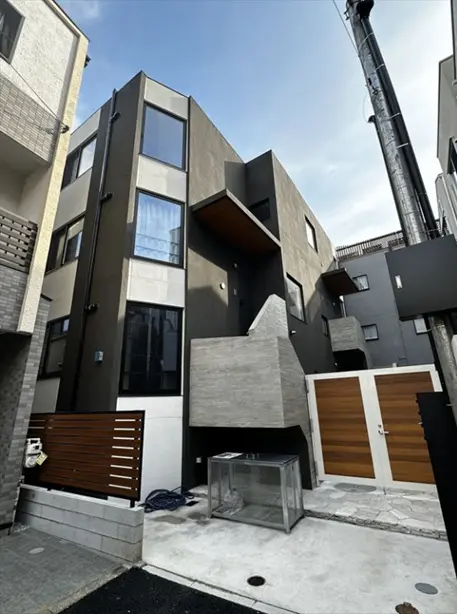 - モダンなデザインの外観を持つ住宅、黒い外壁と大きな窓、木製の扉が特徴のエントランスエリア