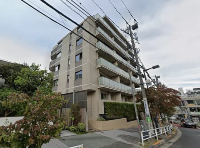 - 都市部に位置するモダンな集合住宅、灰色の外観とバルコニー、周囲に緑がある風景