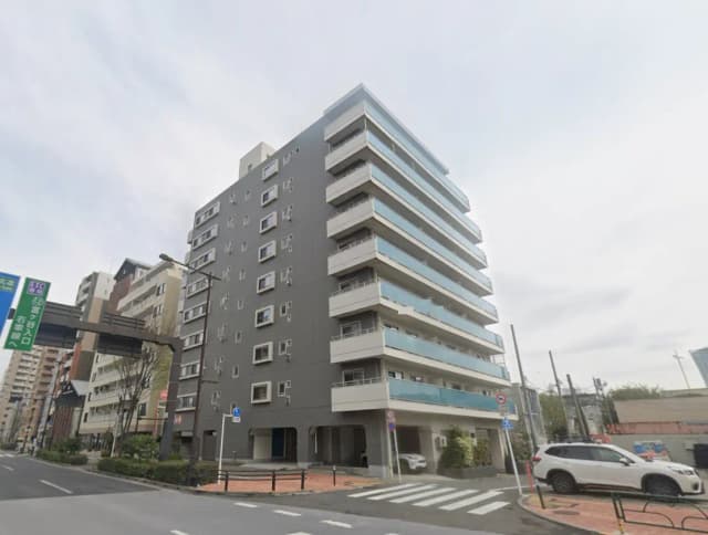 - 都市型マンションの外観、モダンなデザインのファサードとバルコニー、周囲の街並みが見える風景