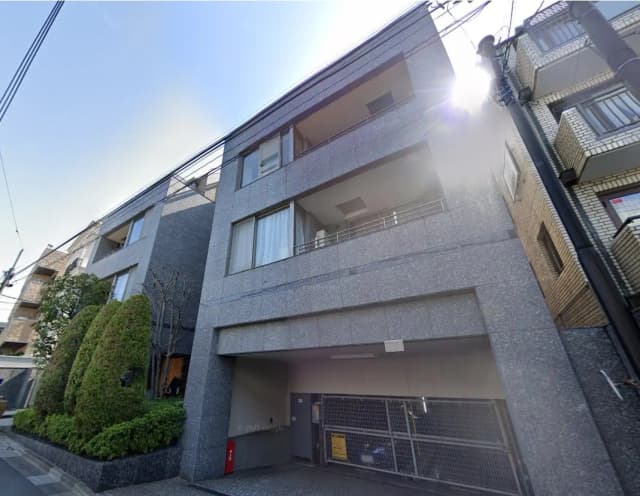 モダンな外観のマンション、グレーの壁と緑の生け垣が特徴的な都市の住宅