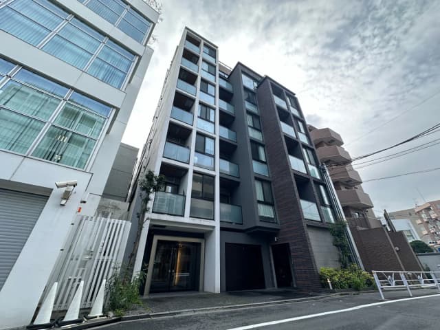 都市の中のモダンなマンション、ダークカラーの外装、ガラス張りのエントランス