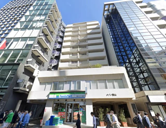 都心に位置する高層ビル群、ファミリーマートの看板が見える商業施設、歩行者が行き交う都市の風景