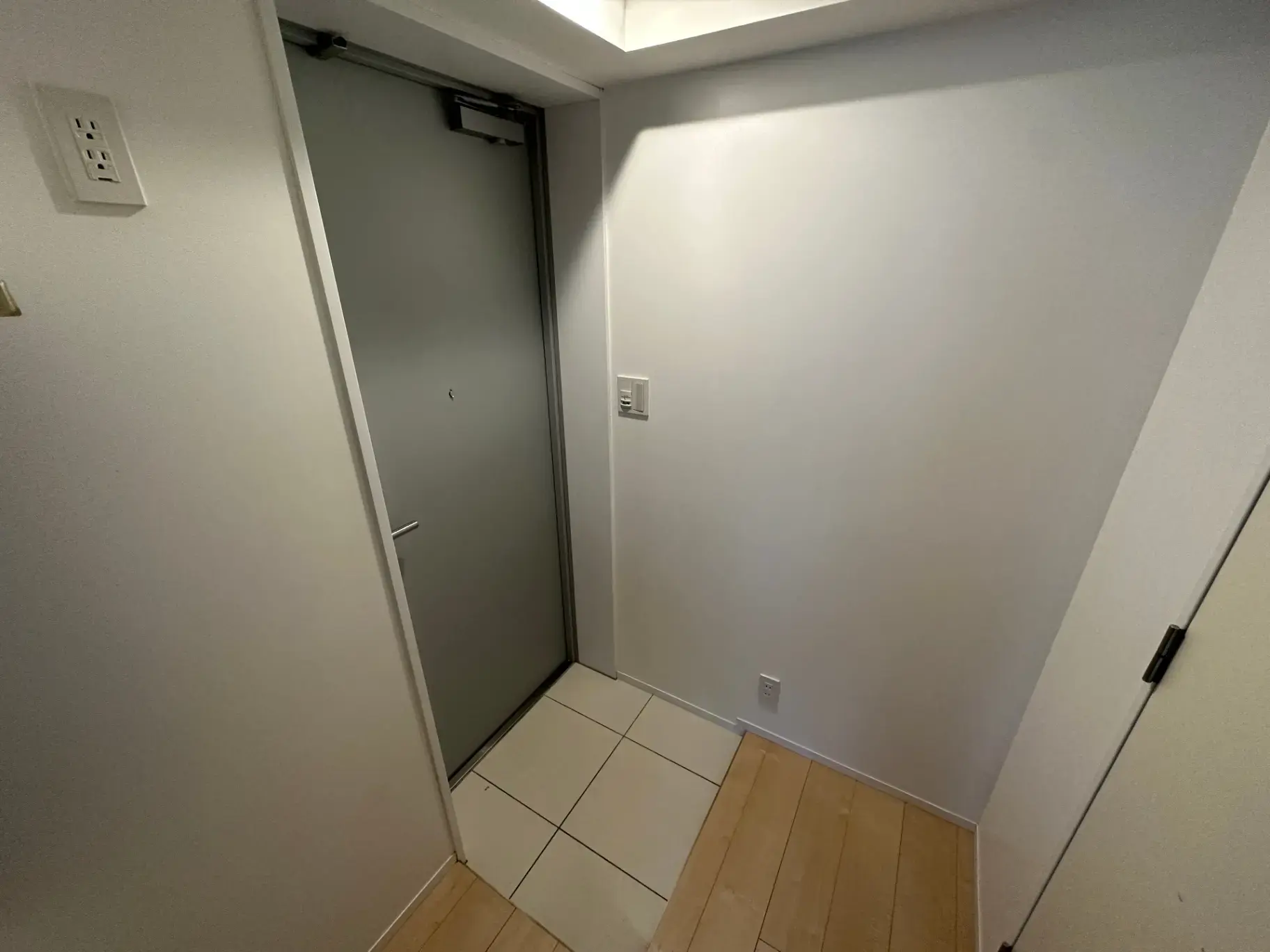 モダンな住宅の玄関ホール、白壁と木製フローリング、スライドドア