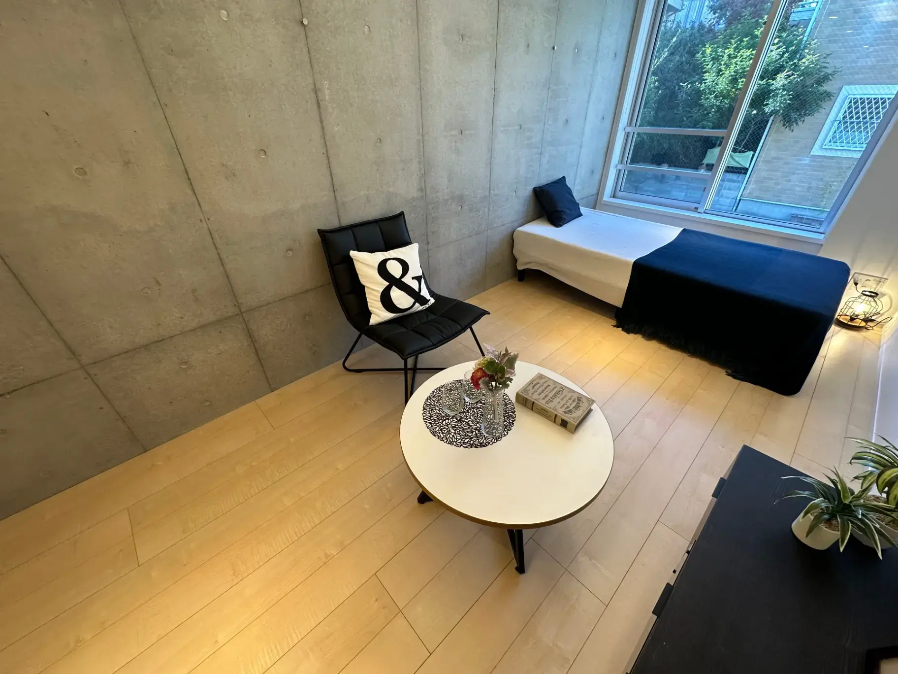 コンクリート打ちっぱなしの壁とナチュラルなフローリングのおしゃれなリビングルーム