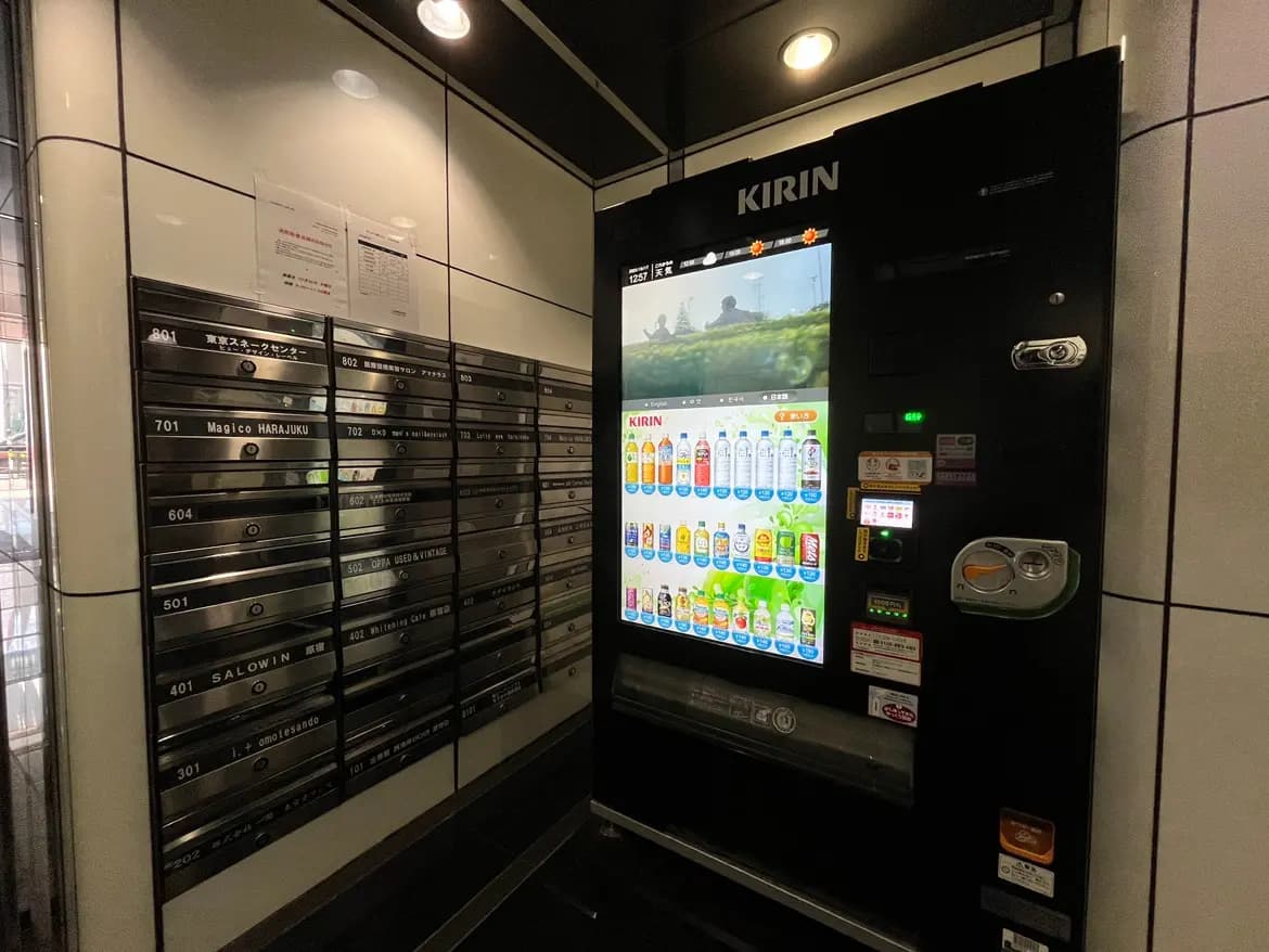 - キリンの自動販売機と郵便受けが並ぶエントランスホールの内部、モダンなデザインと明るい照明の空間