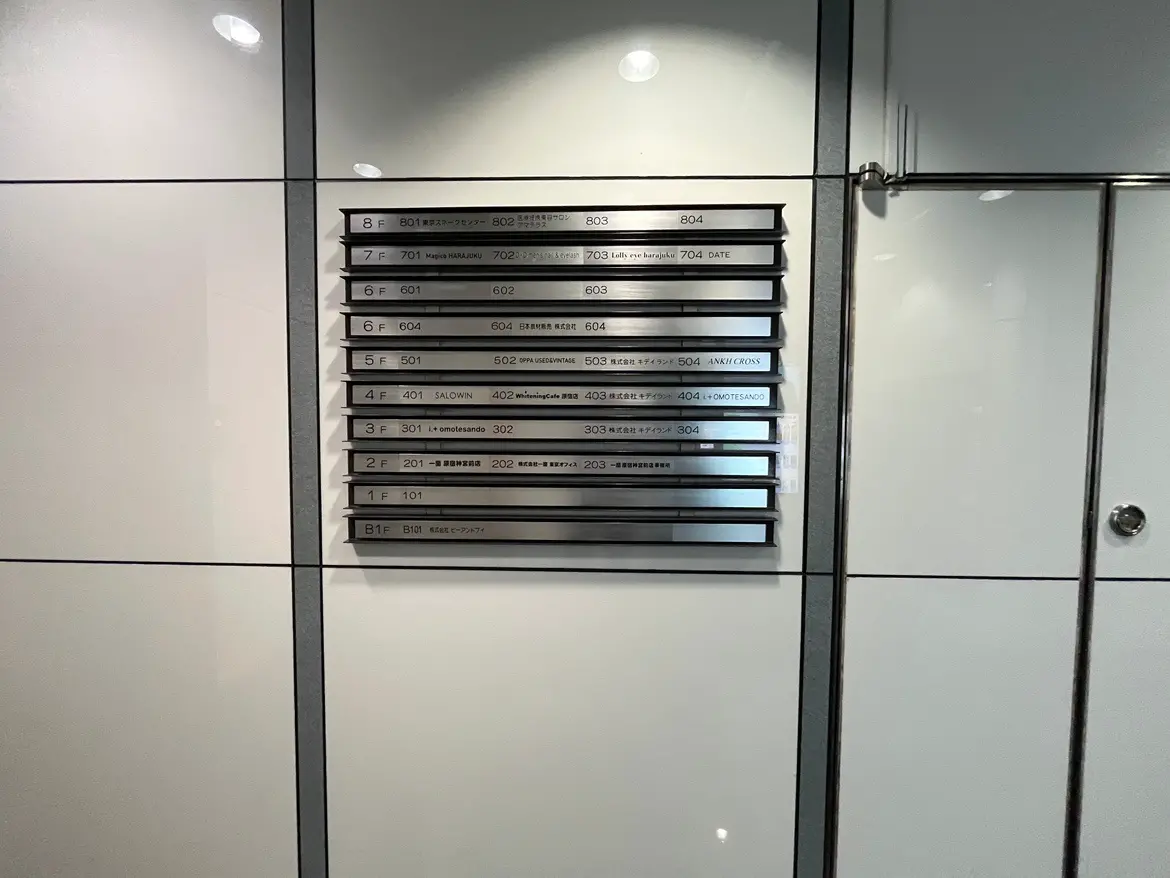 - 複数階の部屋番号と会社名が記載されたエレベーターボード、モダンなデザインの壁に取り付けられているインフォメーションプレート