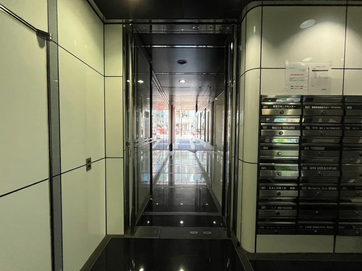 - 近代的なデザインのエントランスホール、ガラスドアとスタイリッシュな郵便受けが並ぶ長い廊下