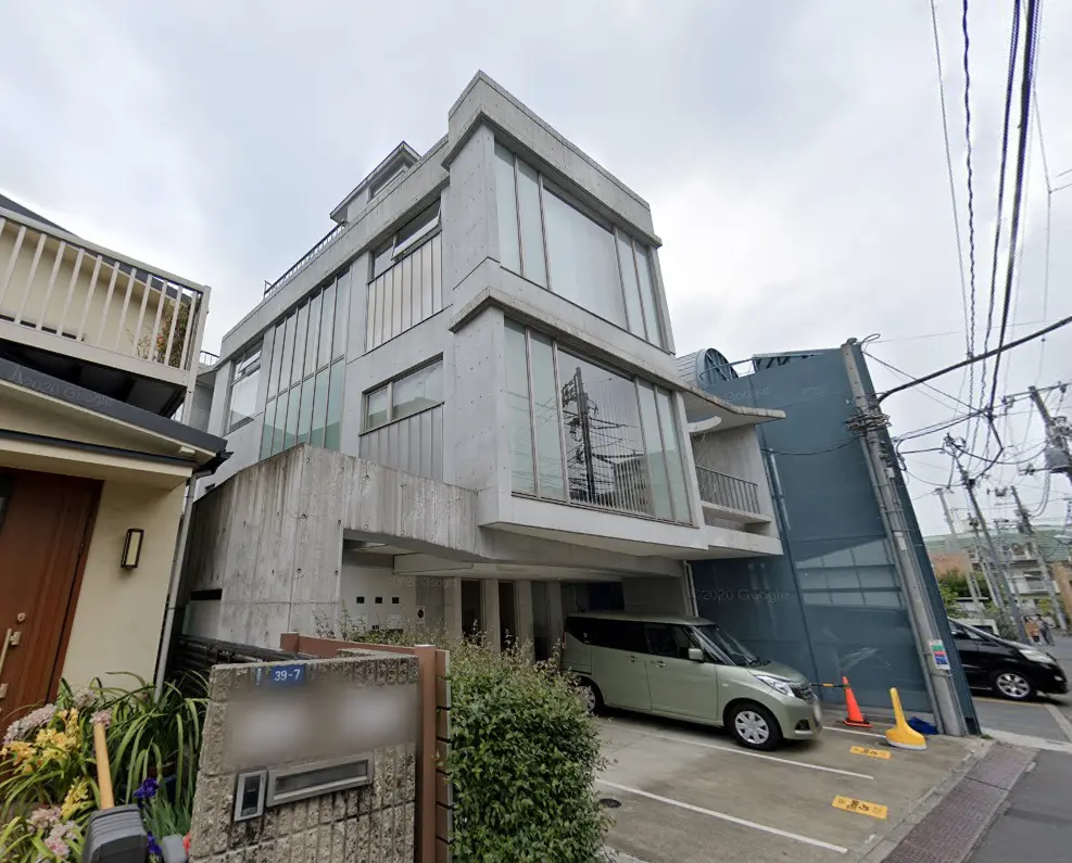 現代的なデザインのコンクリート打ちっ放しの外観、大きな窓とバルコニーが特徴的な都市型住宅