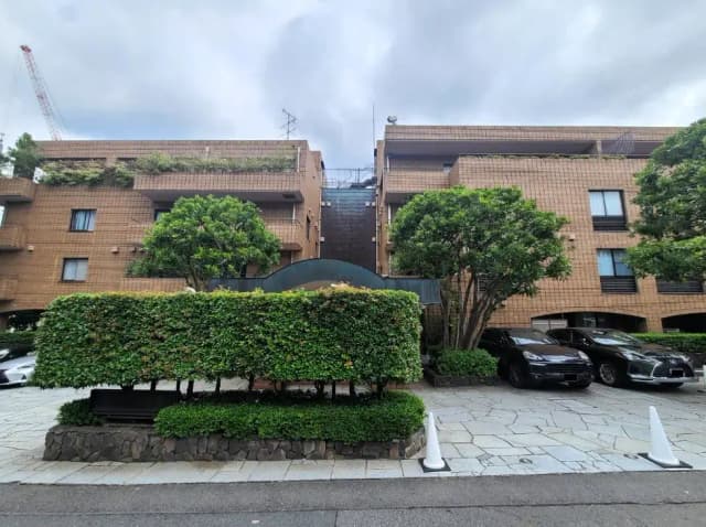 茶色のタイル外装が特徴的な現代的なアパートメント建物、緑豊かな植栽と駐車場のある外観