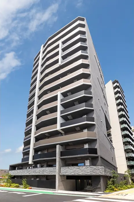 - 現代的なデザインの高層マンション、バルコニーが特徴的で青空の下にそびえる外観の写真